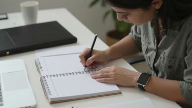 Pessoa organizando tarefas em um planner sobre uma mesa bem iluminada, demonstrando foco e disciplina