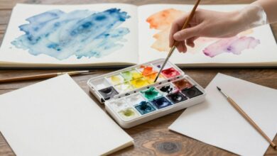 Imagem de capa mostrando uma paleta de aquarela, pincéis e papéis brancos prontos para pintura