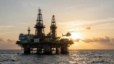 Uma imponente plataforma de petróleo no meio do oceano durante o nascer do sol, com um helicóptero se aproximando para pouso, ilustrando o dinâmico ambiente das profissões para trabalhar embarcado.