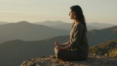 Uma pessoa sentada em uma pose de meditação ao nascer do sol, com uma paisagem serena de montanhas ao fundo, transmitindo uma sensação de paz e calma.